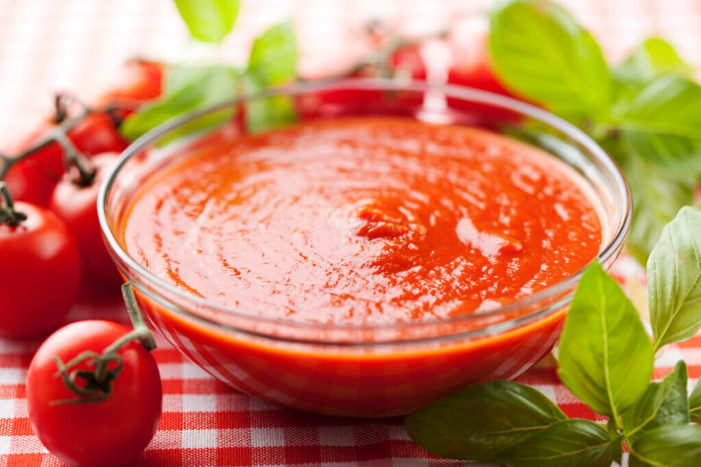 a bowl of tomato sauce sits on a table