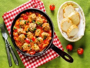 meatballs baked with vegetables on a green background