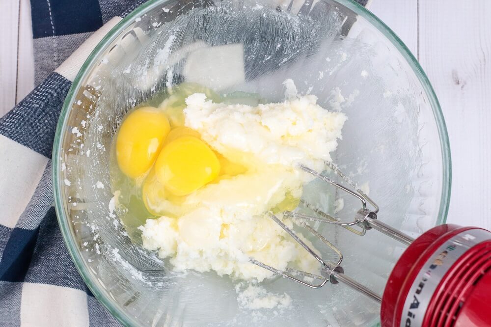 eggs, sugar and butter being mixed in a mixing bowl