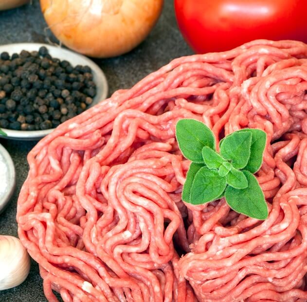 raw ground beef with spices, onions and tomato on a counter
