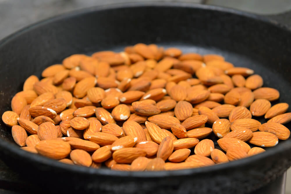 Almonds lightly toasting in a fry pan