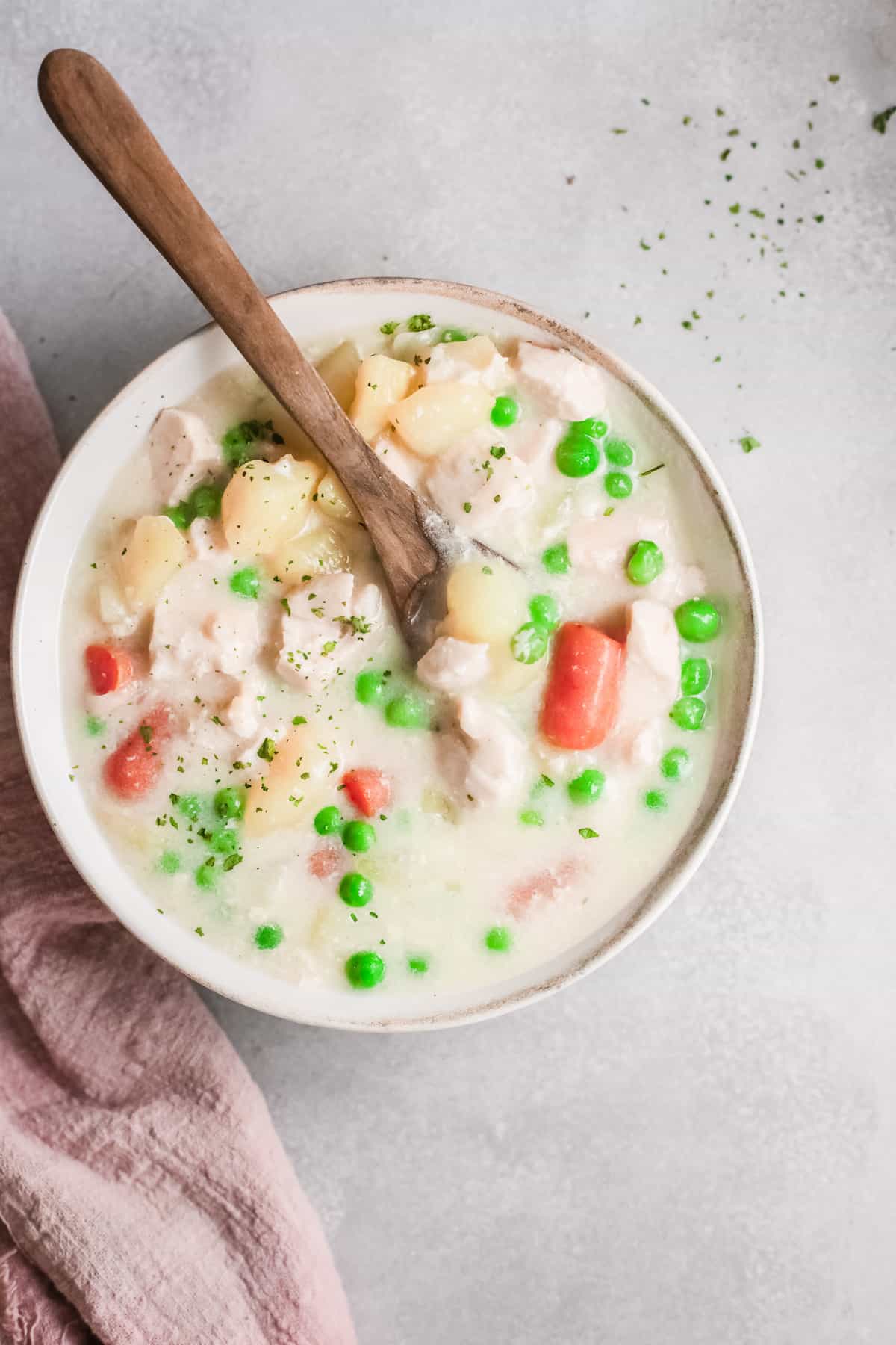 chicken pot pie soup in a bowl with a wooden spoon.